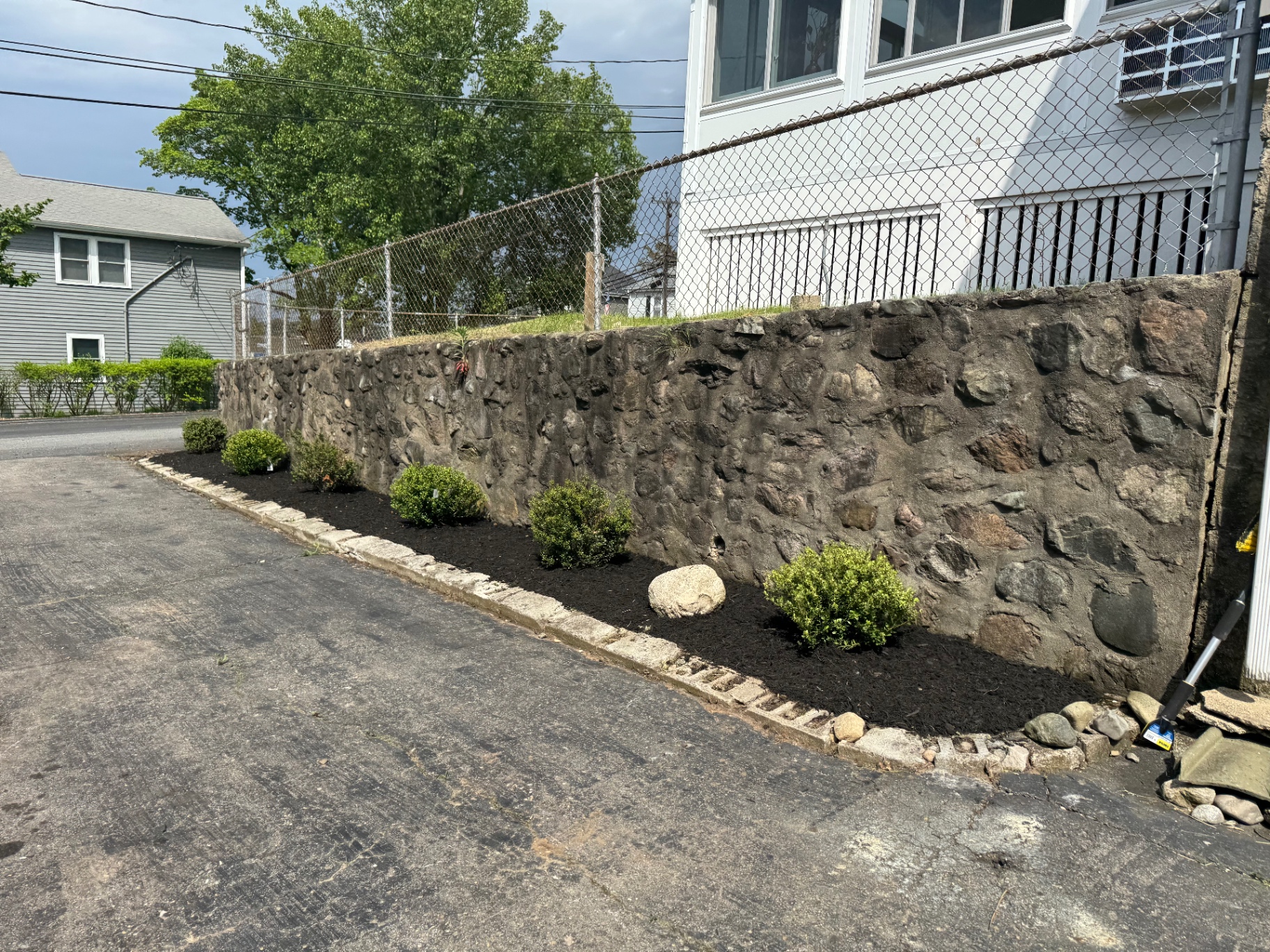 Boxwood plantings and fresh mulch along a fieldstone retaining wall
