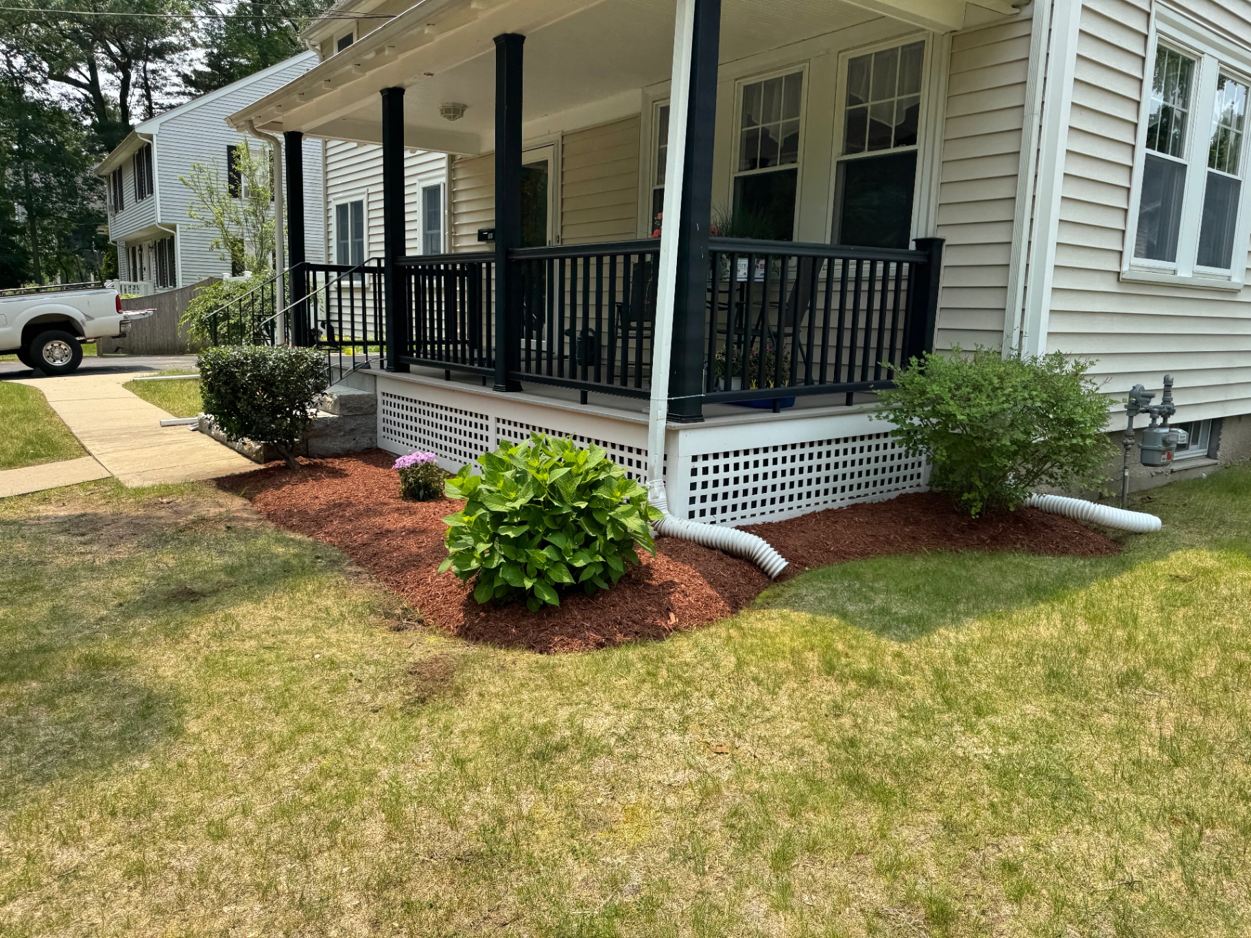 Front porch foundation bed with hydrangea, shrubs, and fresh red mulch