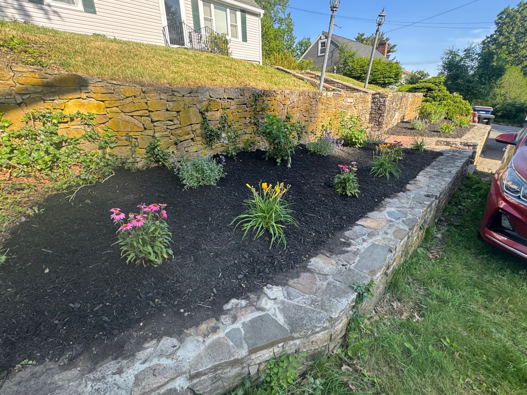 Fresh perennial planting bed set against a natural stone retaining wall