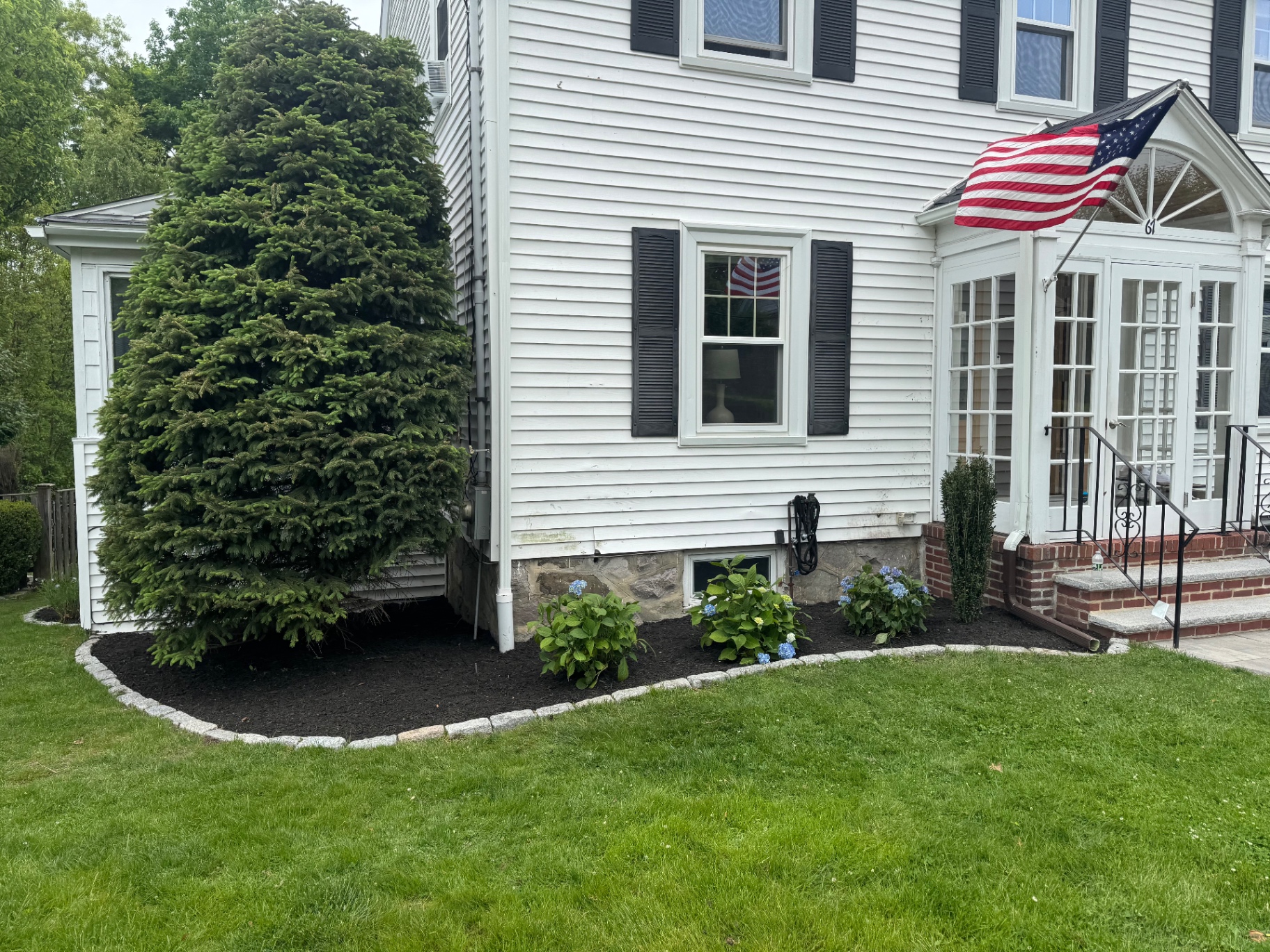 Front foundation bed with hydrangeas, black mulch, and cobblestone edging