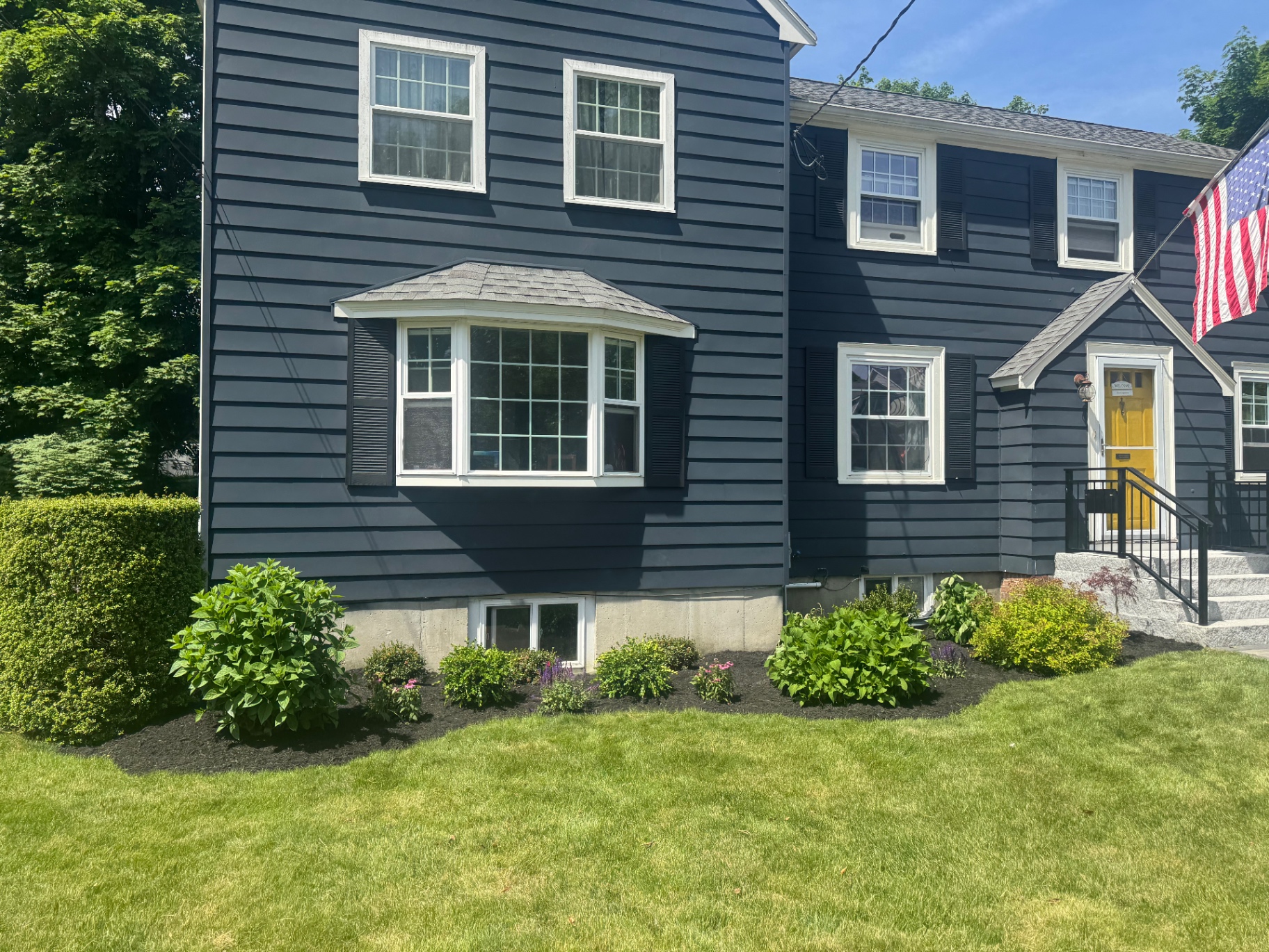 Wide front foundation planting bed at a dark blue home with hydrangeas and shrubs