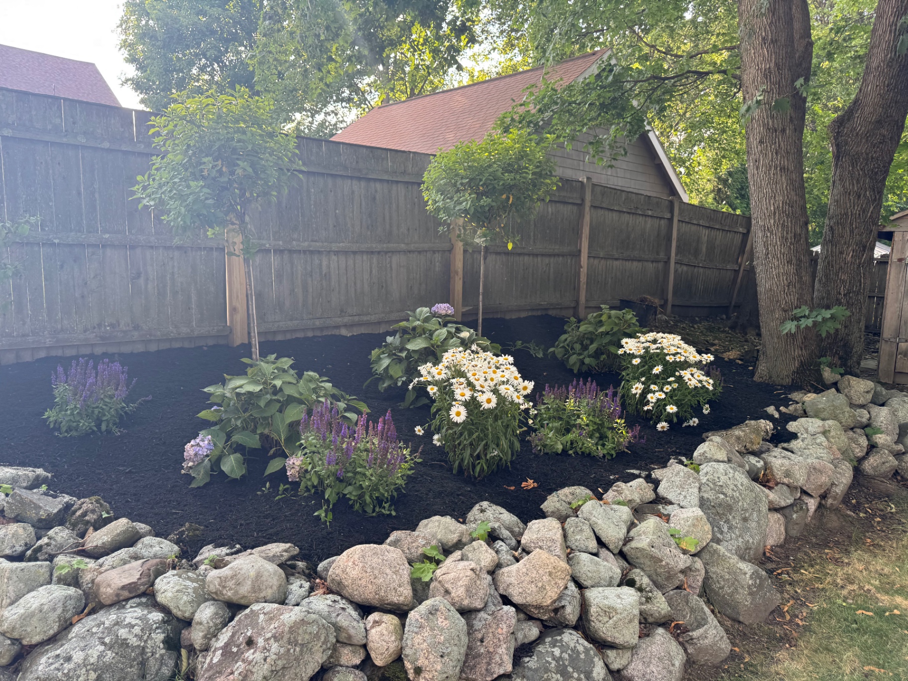 Freshly mulched flower bed with stone border and new plantings
